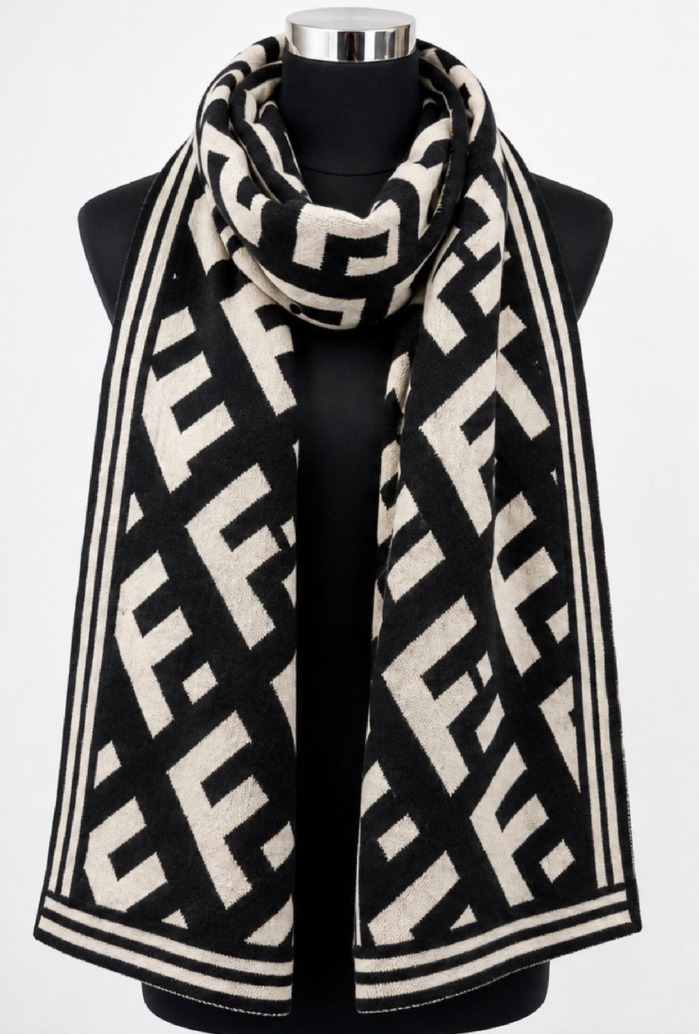 Black and cream geometric monogram patterned winter scarf wrapped around a black mannequin, featuring contrasting striped borders.