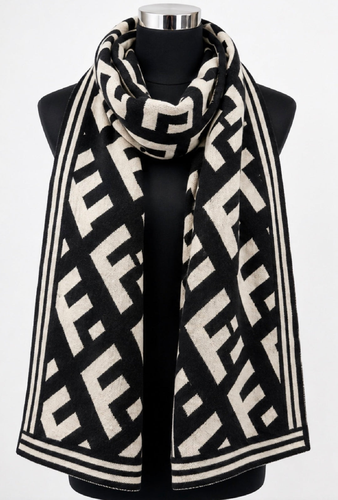 Black and cream geometric monogram patterned winter scarf wrapped around a black mannequin, featuring contrasting striped borders.
