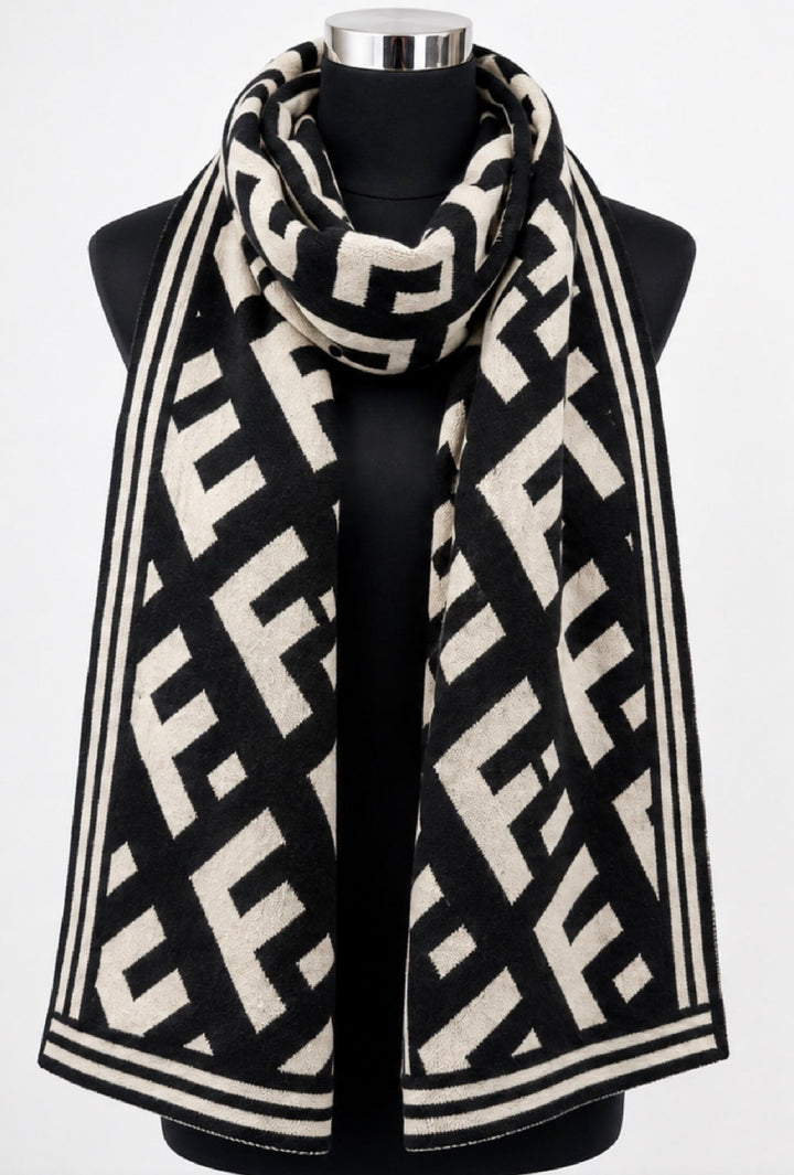 Black and cream geometric monogram patterned winter scarf wrapped around a black mannequin, featuring contrasting striped borders.