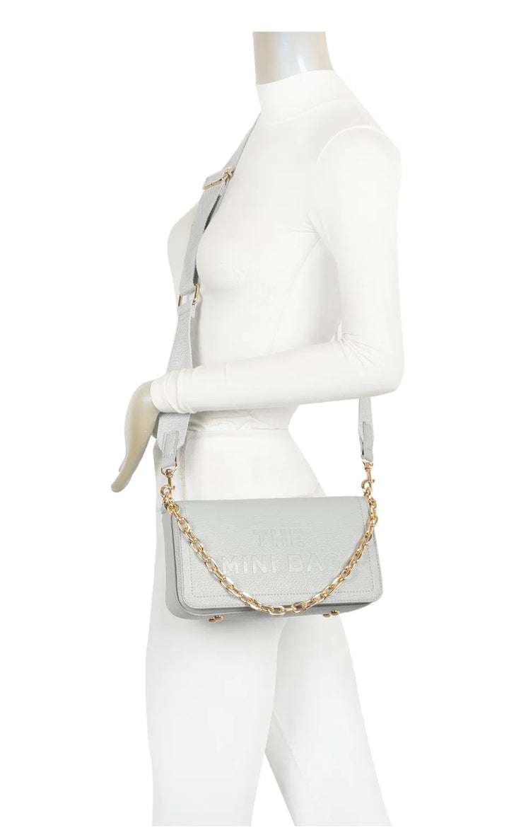 A grey mini tote bag with a chain detail and the text &