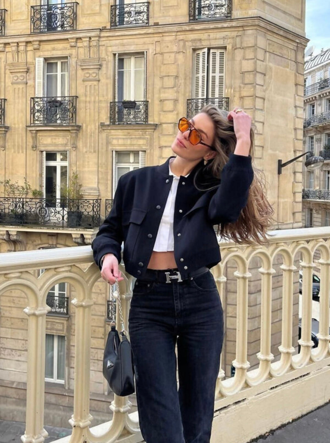 Black cropped bomber jacket styled with jeans and handbag, chic outfit