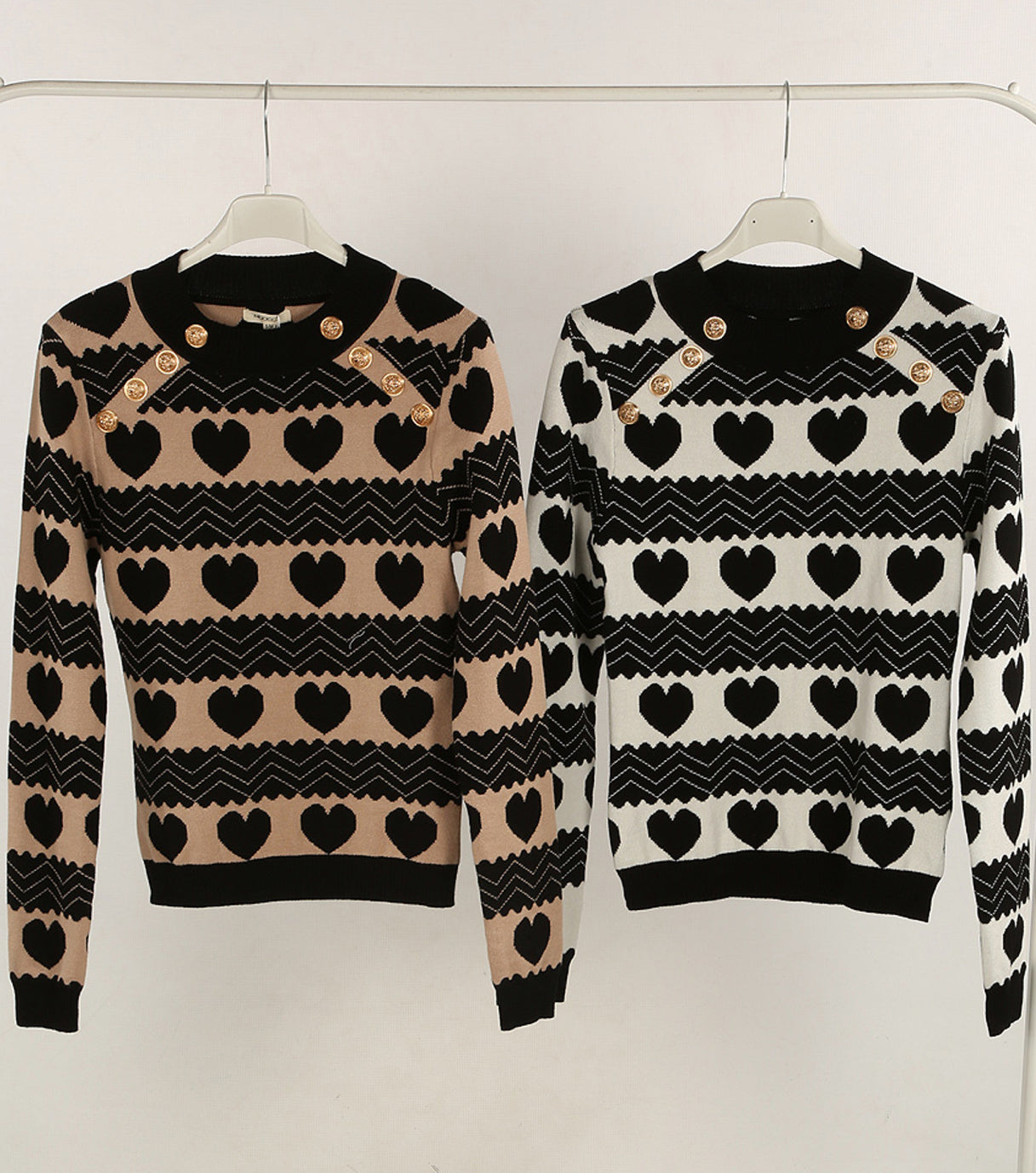 Two sweaters with heart and zigzag pattern on hangers
