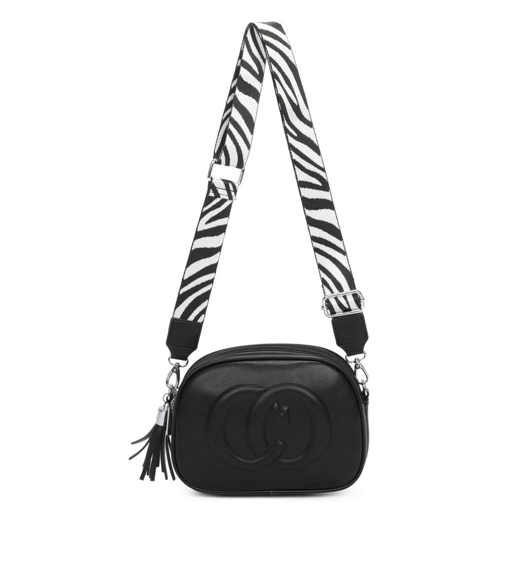 A black and white zebra patterned strap cross body bag with a detachable and adjustable strap, featuring multiple zipped compartments and golden tone metal hardware.