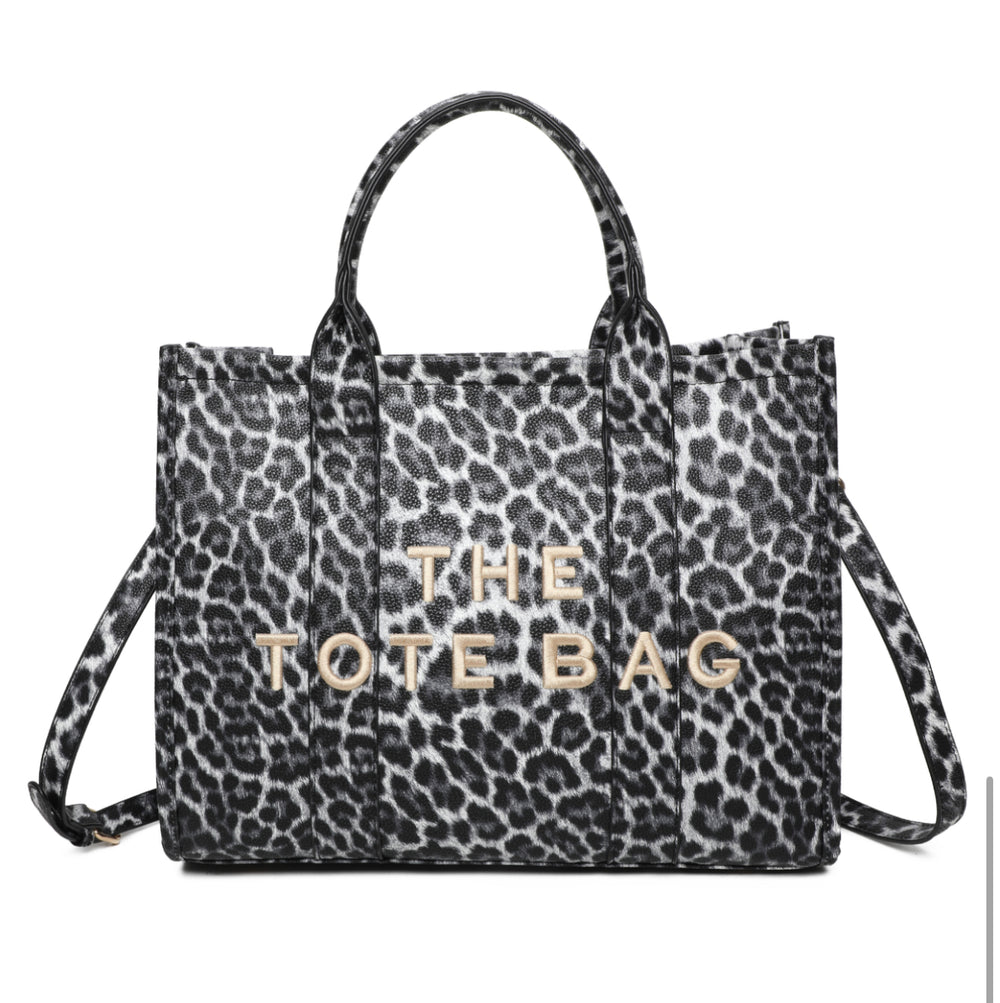 A leopard animal print tote bag with double grab straps and gold tone metal hardware.