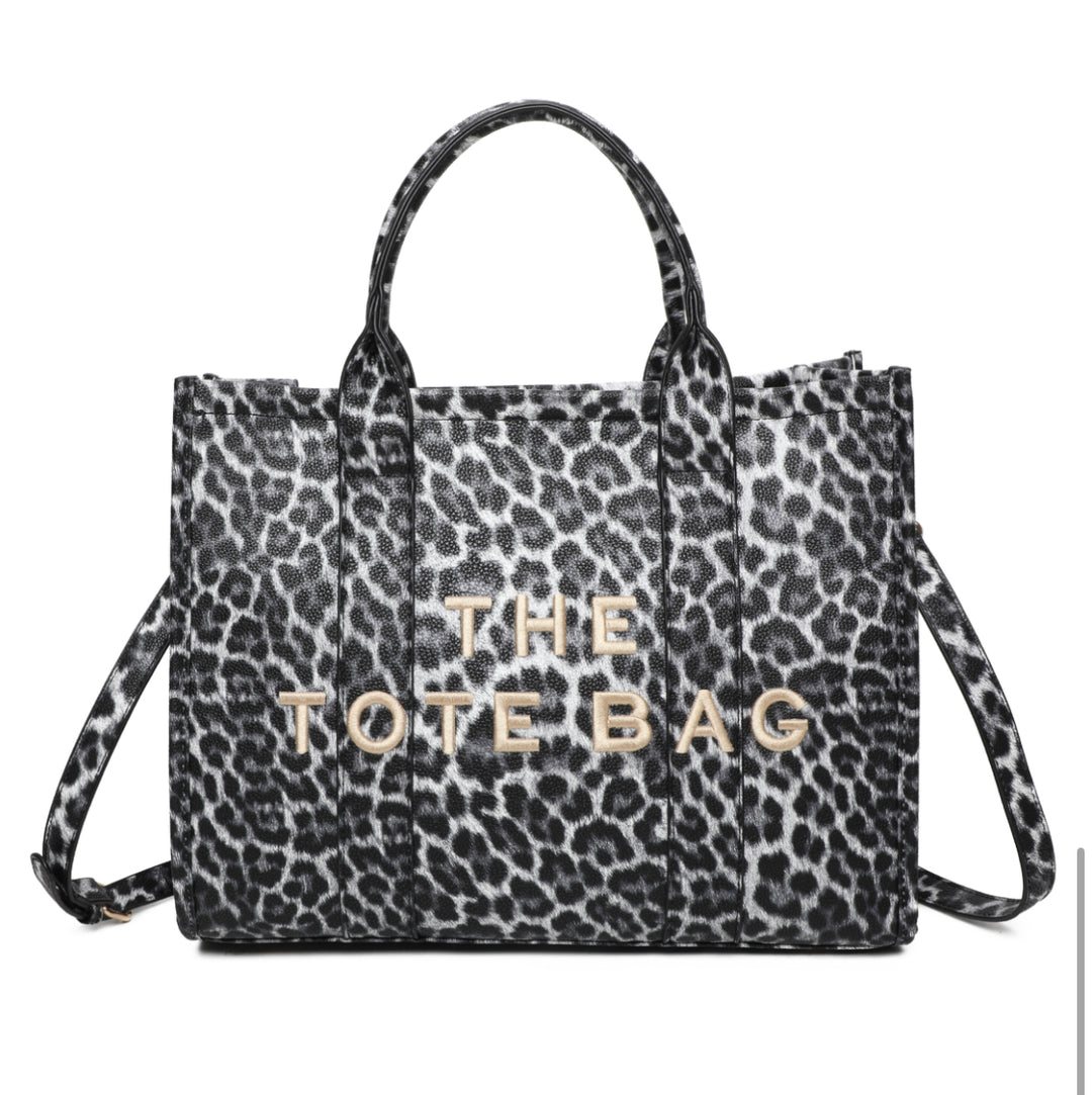 A leopard animal print tote bag with double grab straps and gold tone metal hardware.