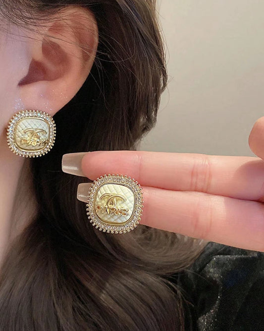 Stud earrings with a crystal frame, gold lettering in a 3d design, cream centre colour of the stud earring