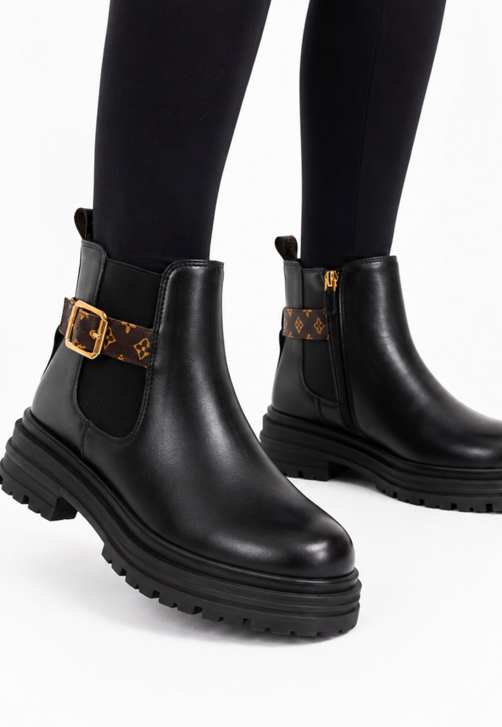 Black chunky Chelsea-style ankle boots with brown printed strap, gold buckle and cleated sole