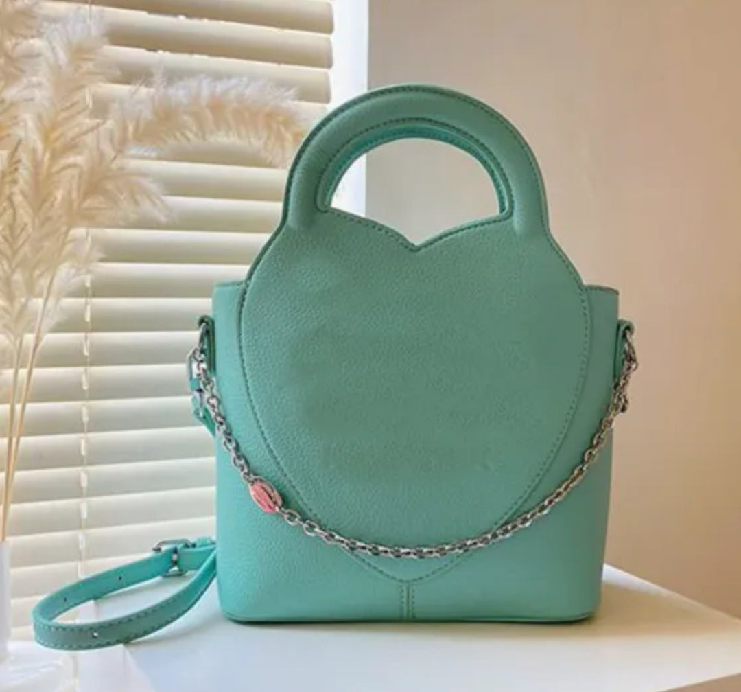 A crossbody handbag with a long strap placed against a window with light coming through.