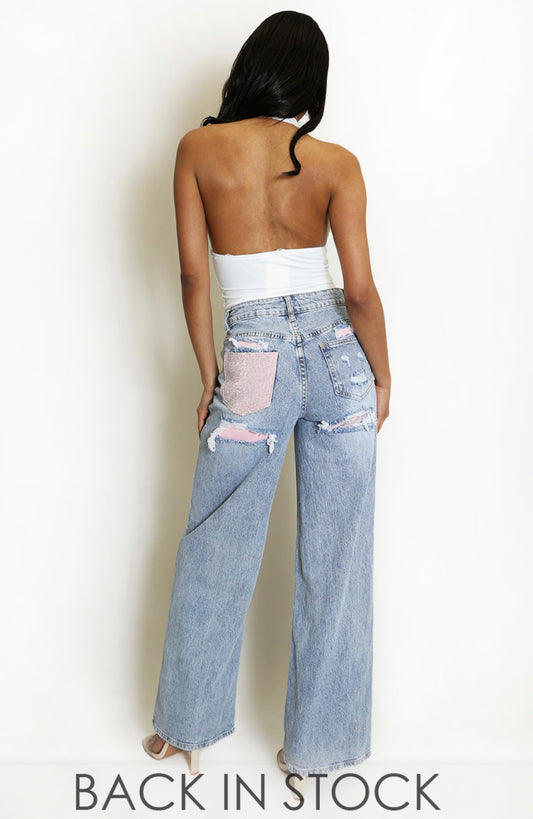 Light wash wide leg distressed jeans with pink rhinestone detail on back pocket and ripped sections