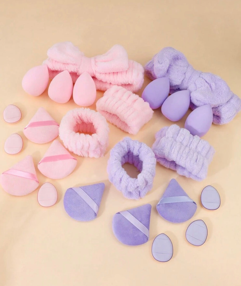 A set of soft, plush makeup sponges and applicator sponges in pastel pink and lavender purple, arranged neatly on a light beige background.