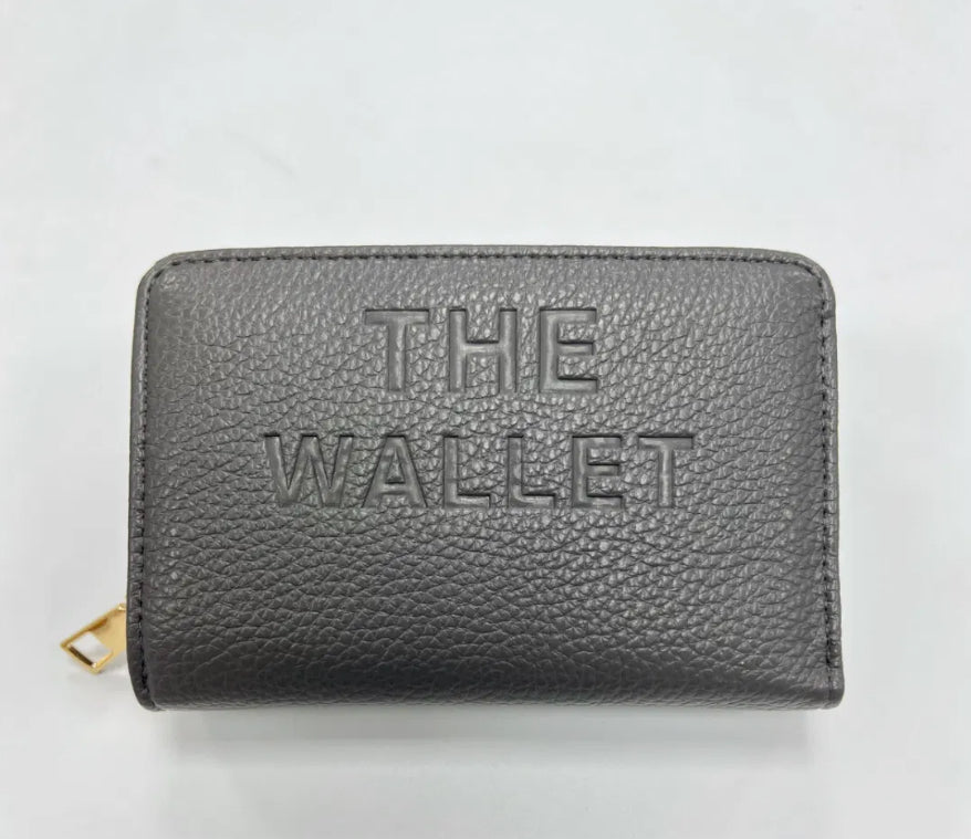 Grey purse with gold hardware and “the wallet” embossed on the front