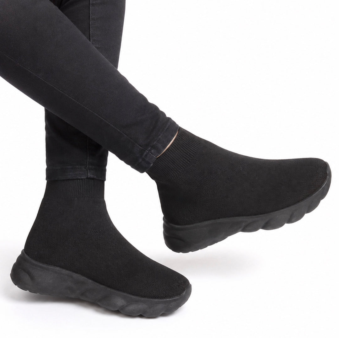 Black knit slip-on socks with chunky black soles, shown on a person&