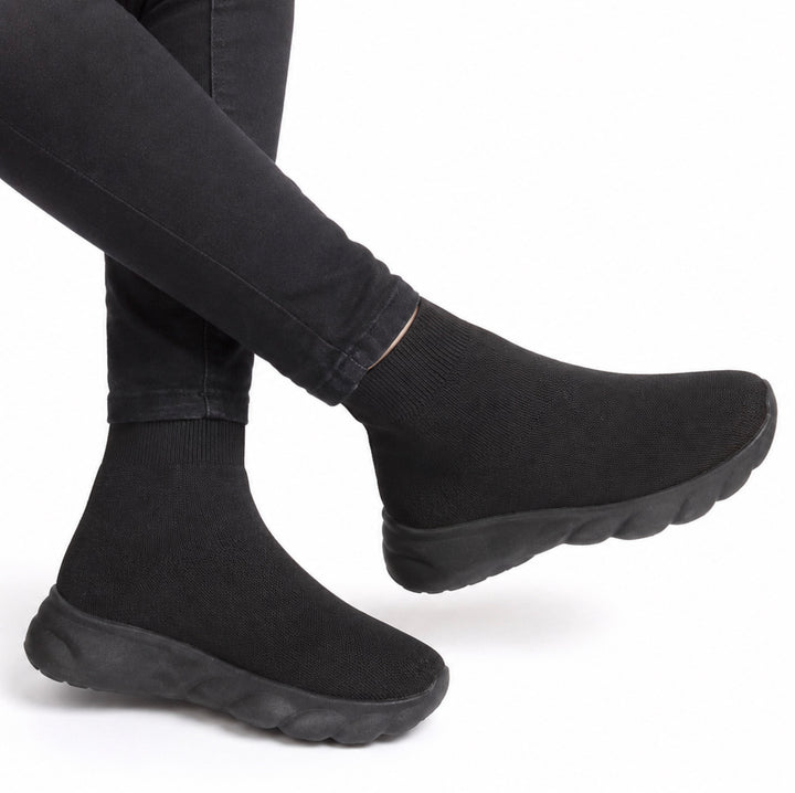Black knit slip-on socks with chunky black soles, shown on a person&