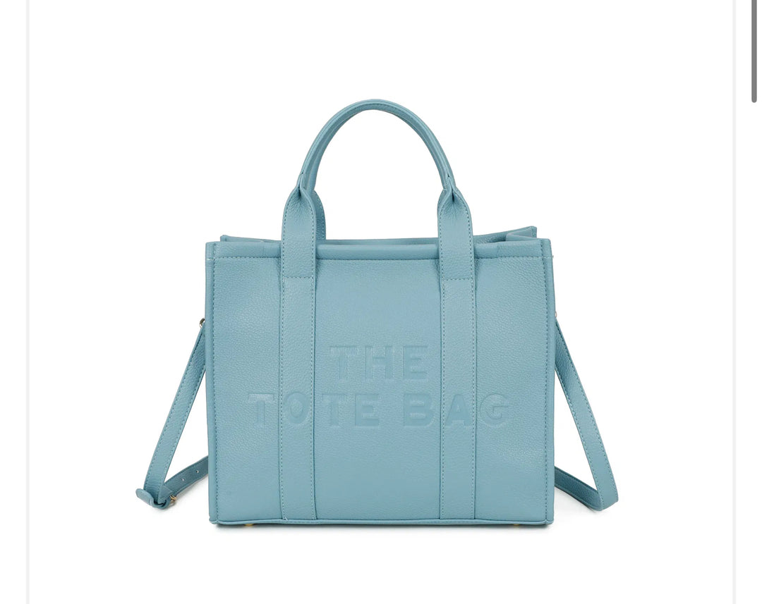 A blue tote bag with embossed ‘The Tote Bag’ text, structured design with top handles and detachable shoulder strap