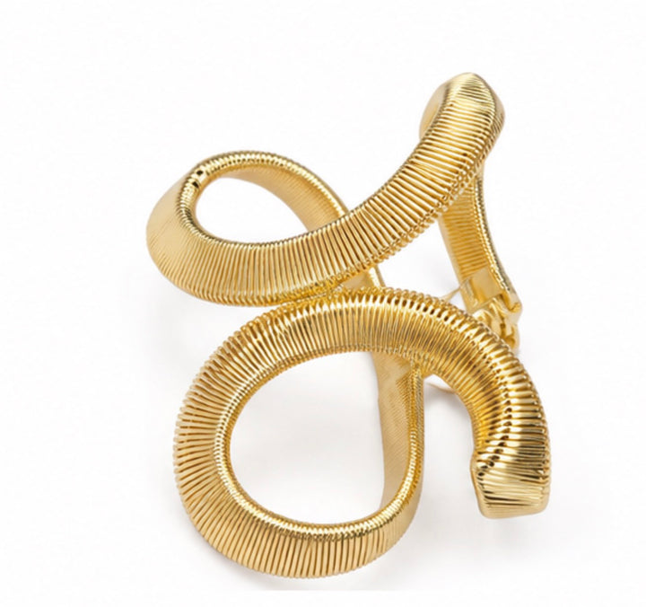 Gold sculptural twist cuff bangle bracelet with a textured finish displayed on a white background.