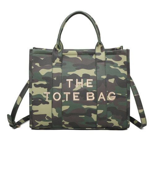 A camouflage tote bag with the text 'THE TOTE BAG' printed in large letters on the front. The bag has green, brown, and black colors, typical of a camo pattern, and features a shoulder strap, a hand carry handle,