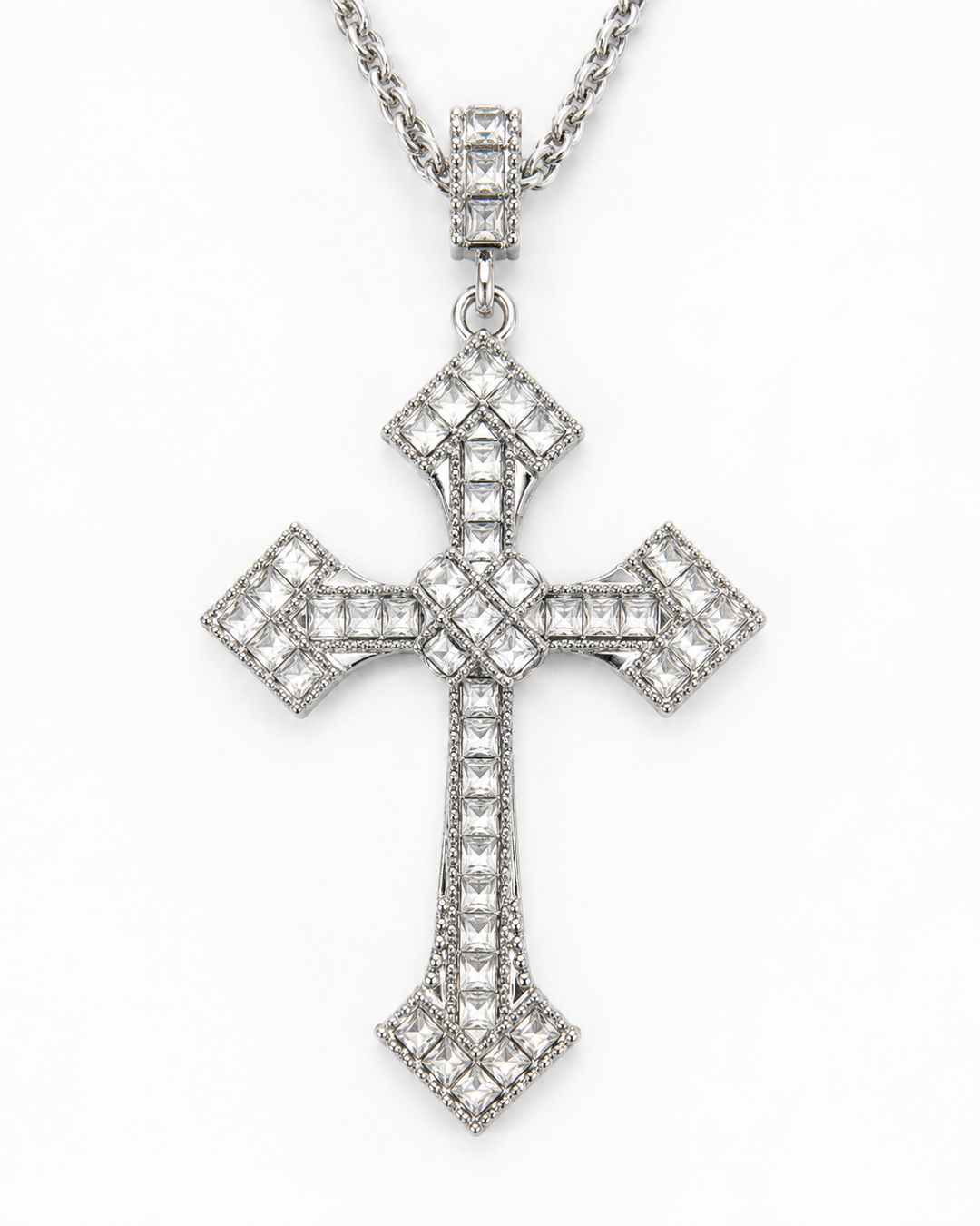 A silver-toned cross pendant necklace paved with clear stones, hanging from a matching chain against a plain white background.