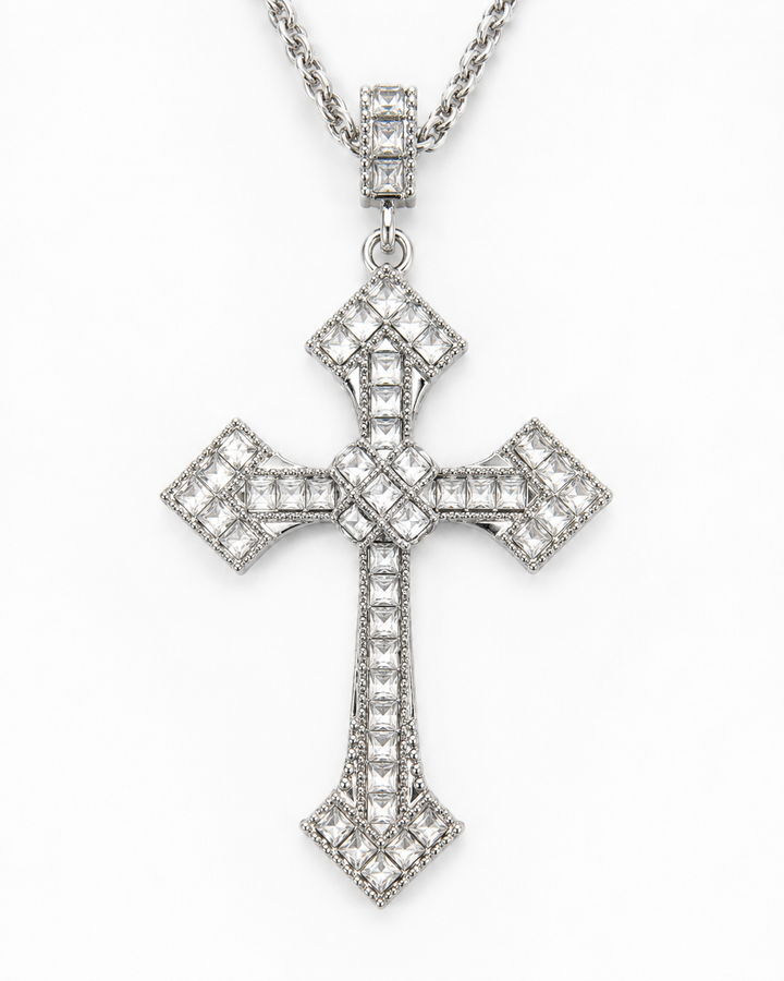 A silver-toned cross pendant necklace paved with clear stones, hanging from a matching chain against a plain white background.