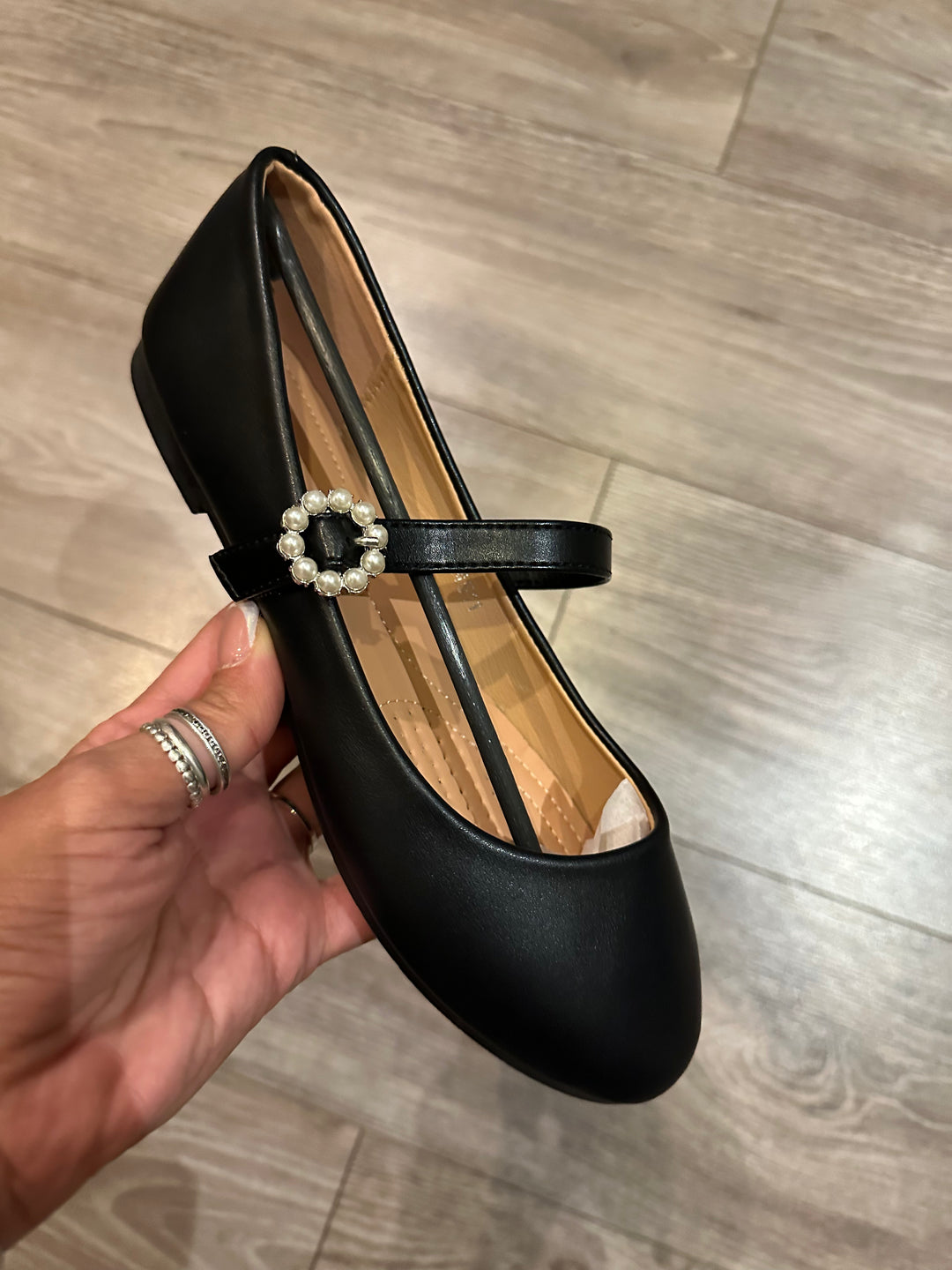 A black faux leather ballet loafer with a pearl fastening detail