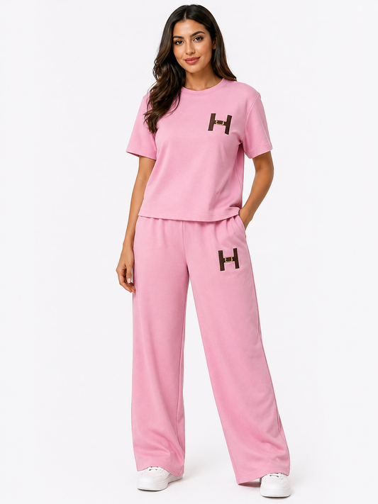 Woman wearing a pink outfit with 'H' logo on a white background