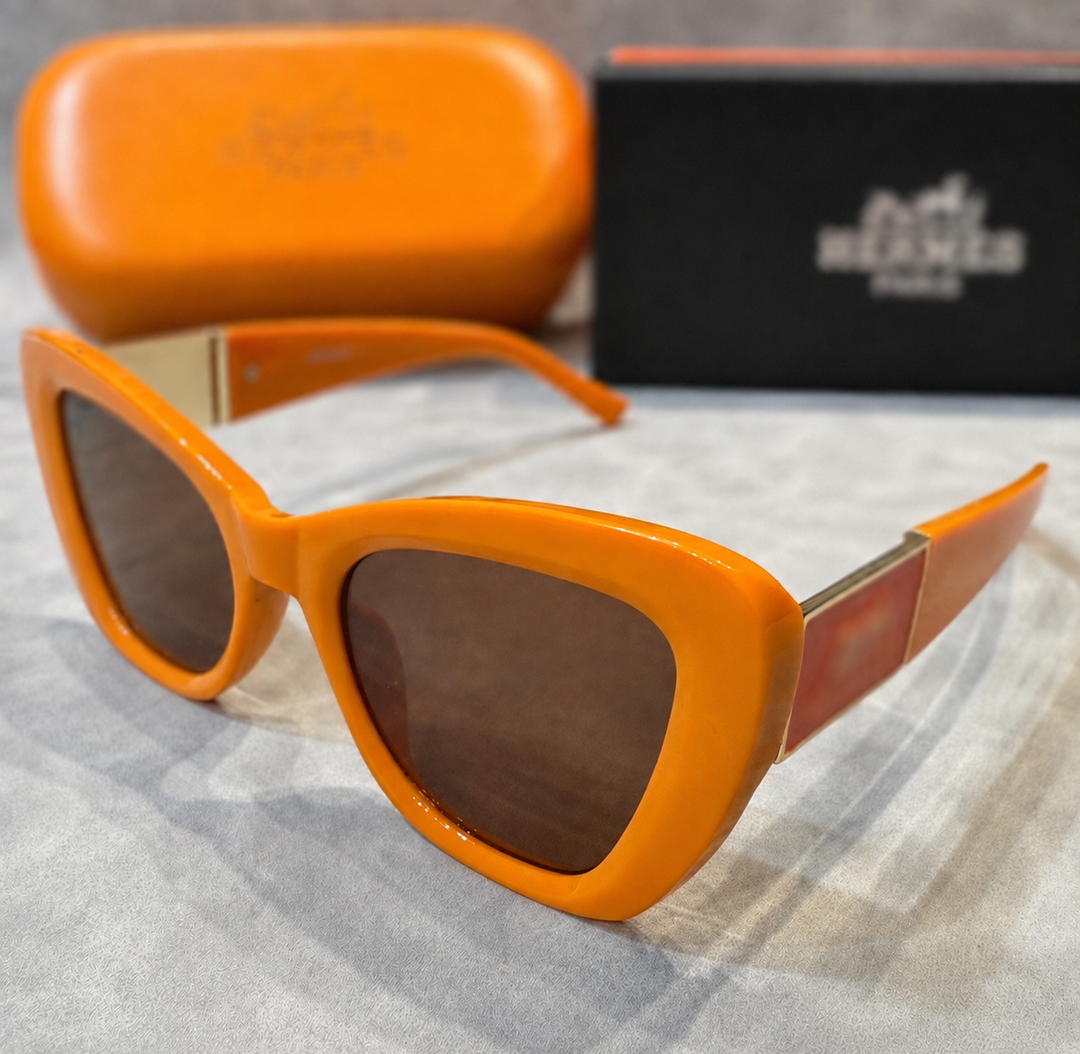 Oversized orange square sunglasses with dark tinted lenses and gold side detail on a neutral background